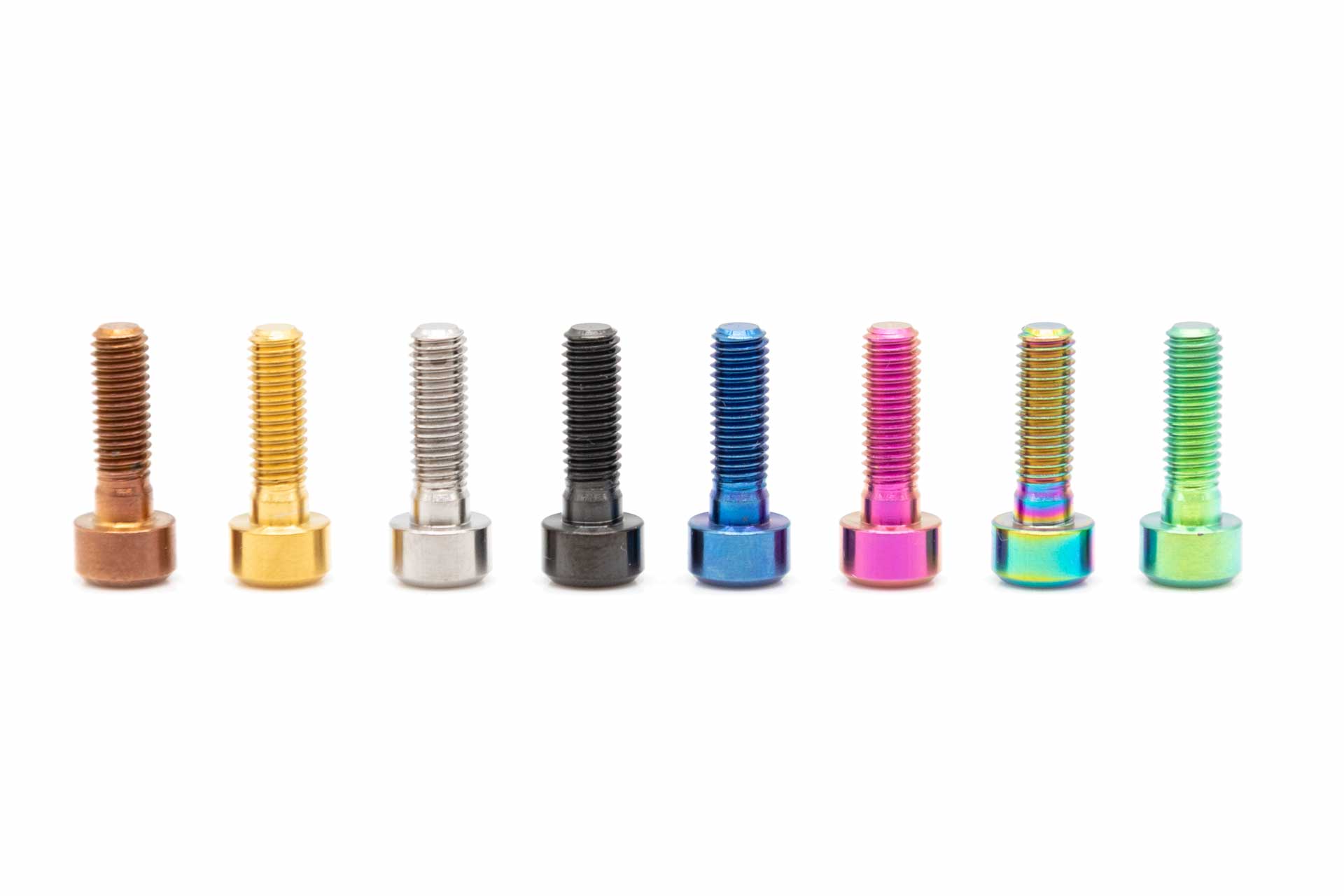 Row of eight colorful metallic mountain bike bolts in various finishes on a white background.