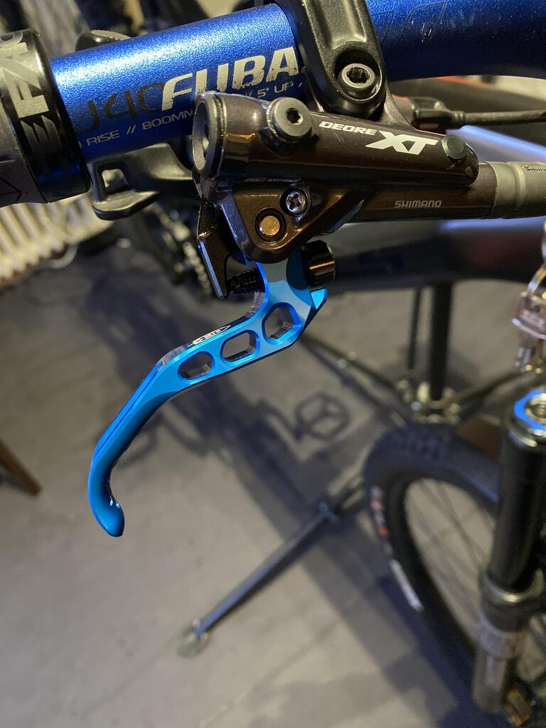 Blue FUBA bicycle handlebar with 800mm rise and black Shimano Deore XT brake lever on mountain bike