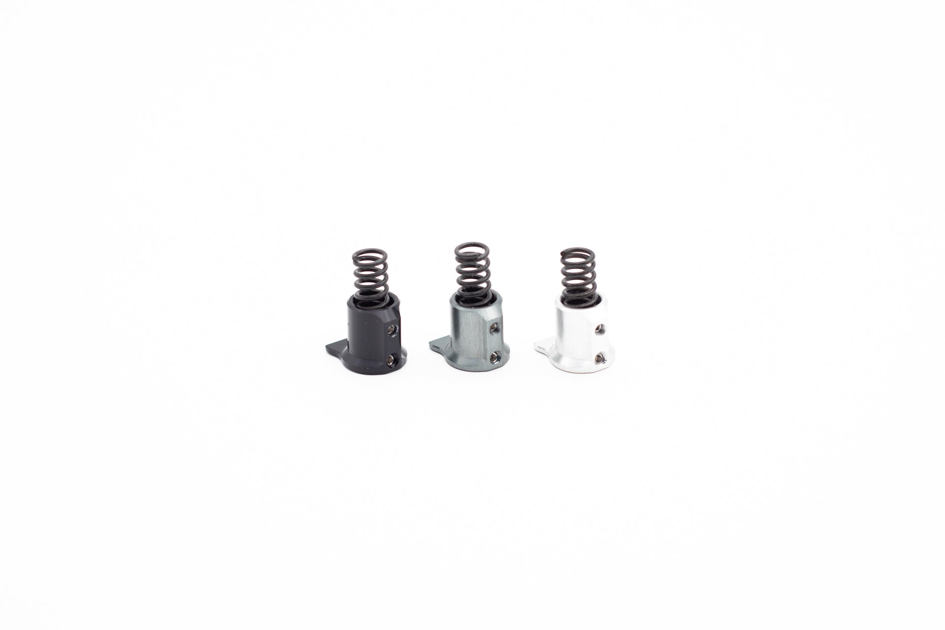 Three precision mountain bike components with coiled springs in black, metallic grey, and white.