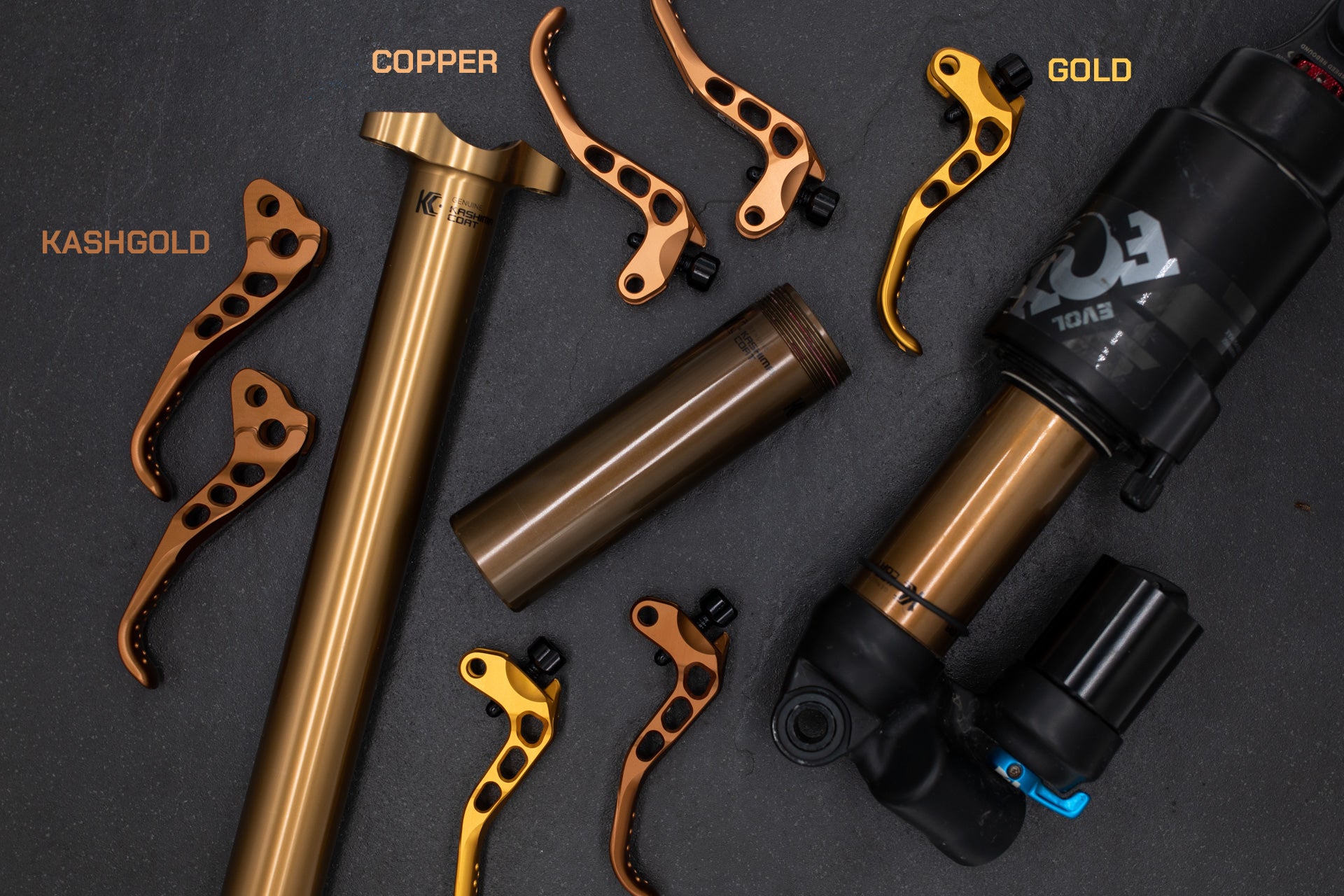 Copper-colored KC Genuine Kashima Coat suspension tube with KASHGOLD copper brake levers on dark surface.
