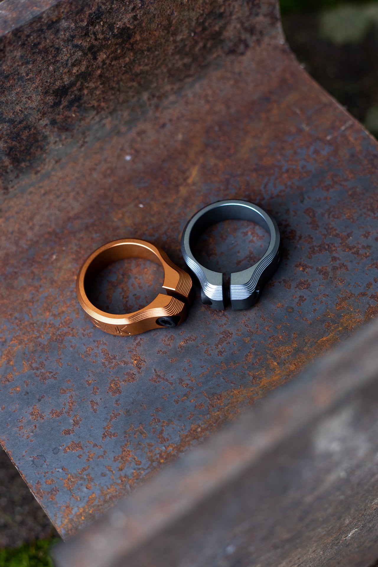 Bronze and silver-black SIX K bike clamps on a rusted surface, showcasing durable components