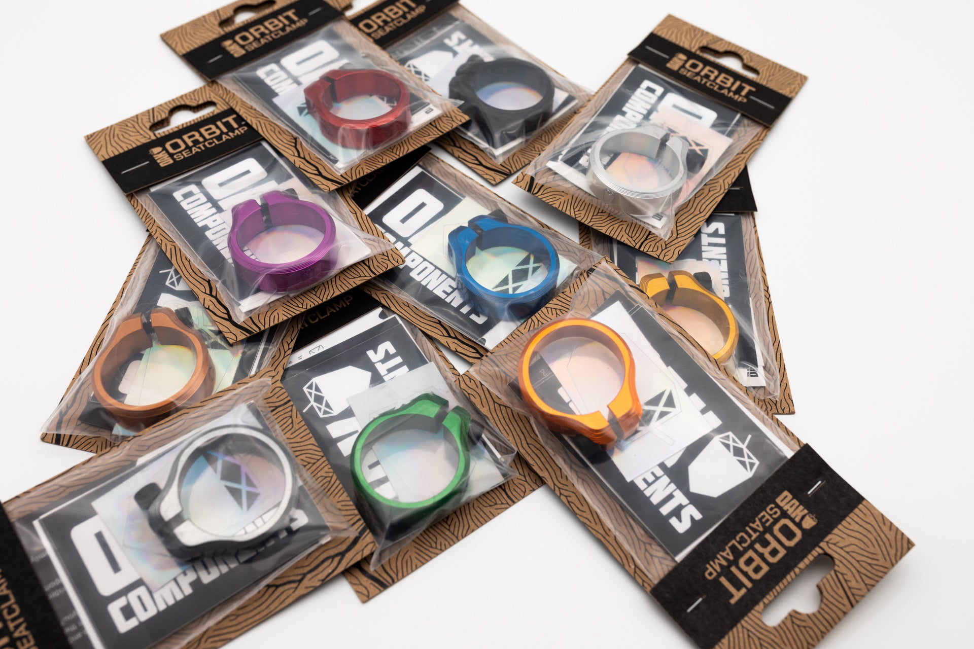 Colorful ORBIT SEATCLAMP bicycle seat clamps in packaging with branded cardboard backing on a white surface