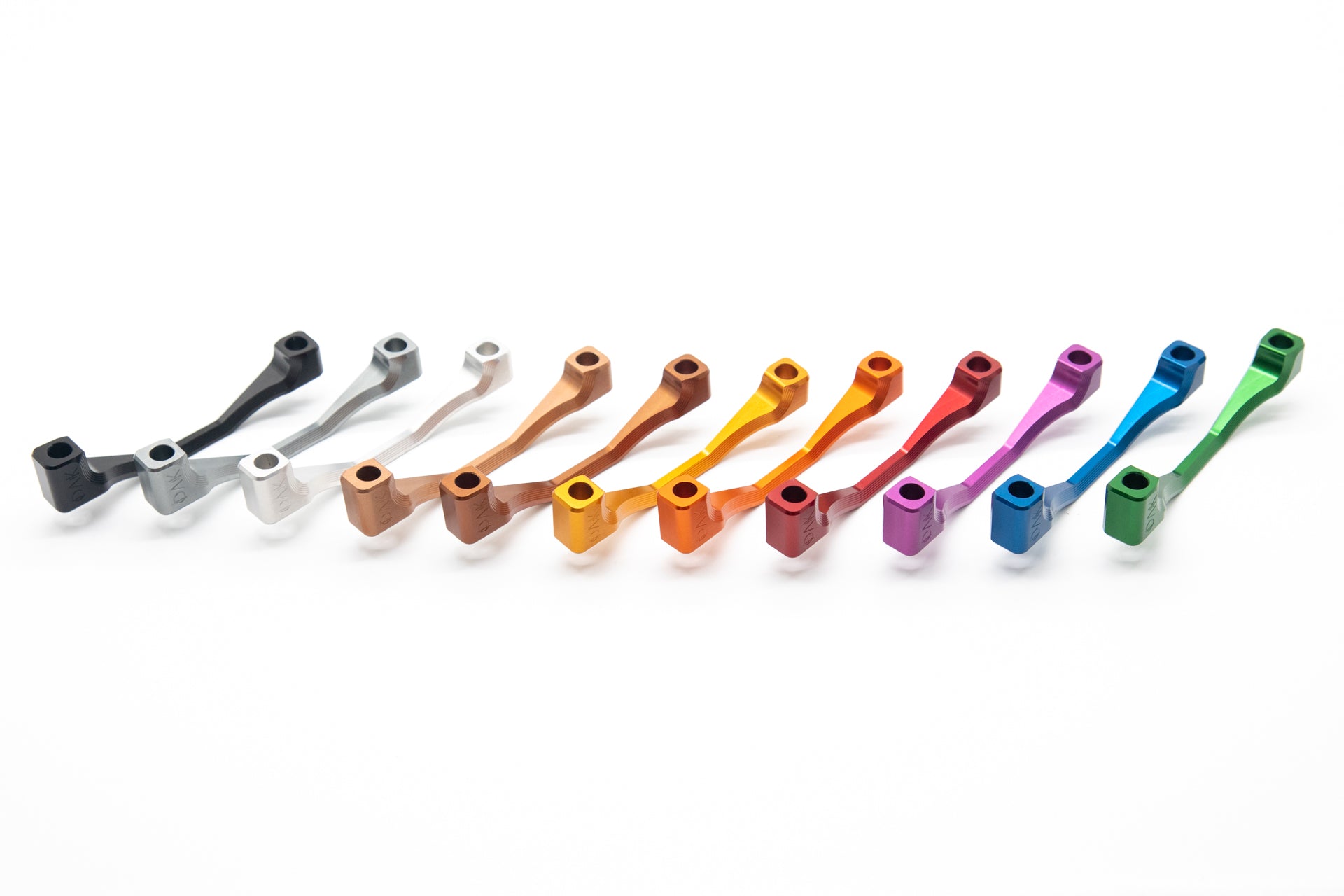 Twelve colorful DMCK engraved metallic levers arranged diagonally, showcasing craftsmanship for mountain bike parts.