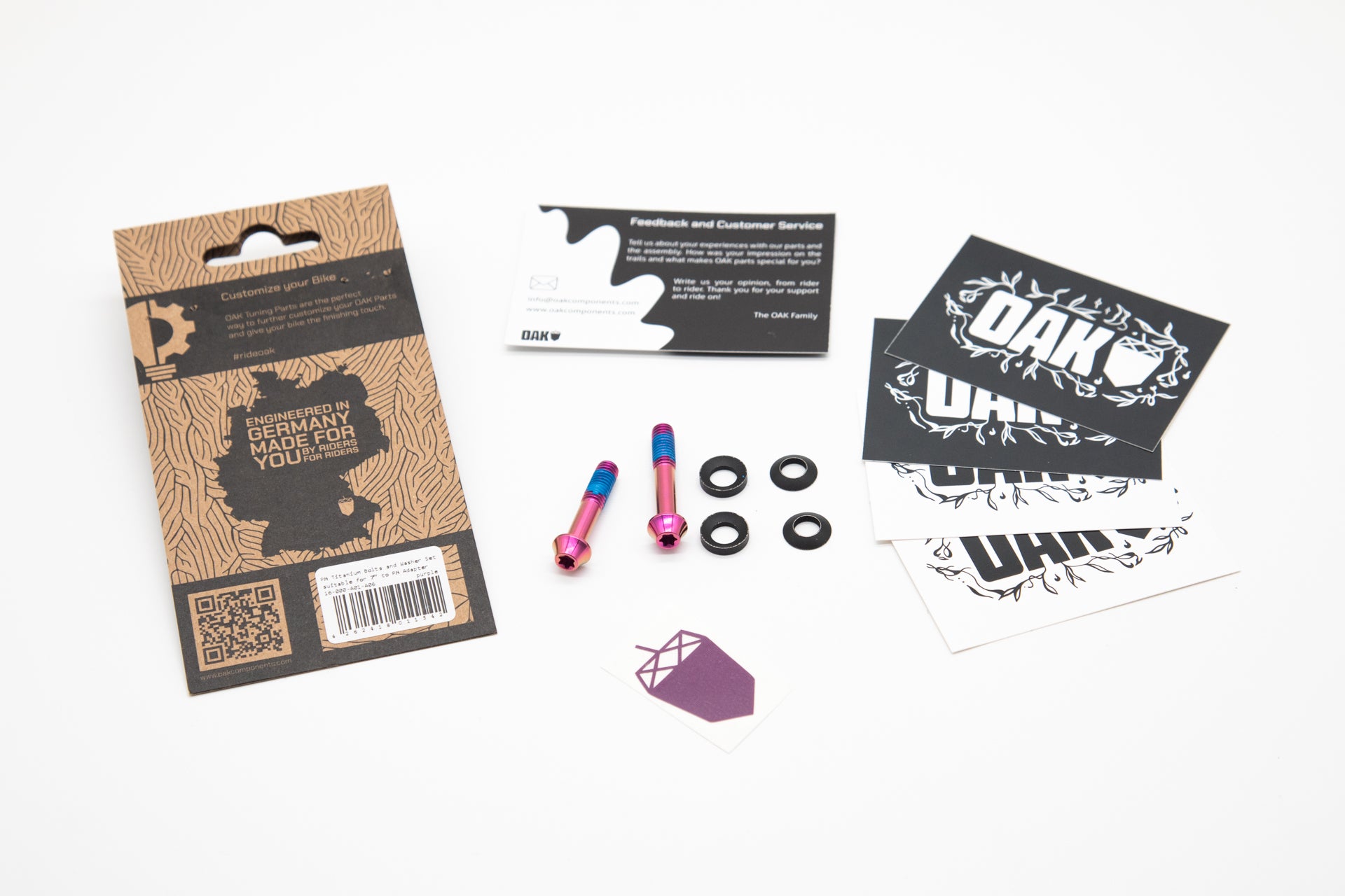 Brown cardboard packaging with OAK branding, colorful titanium bolts with washers, feedback card, and logo stickers.