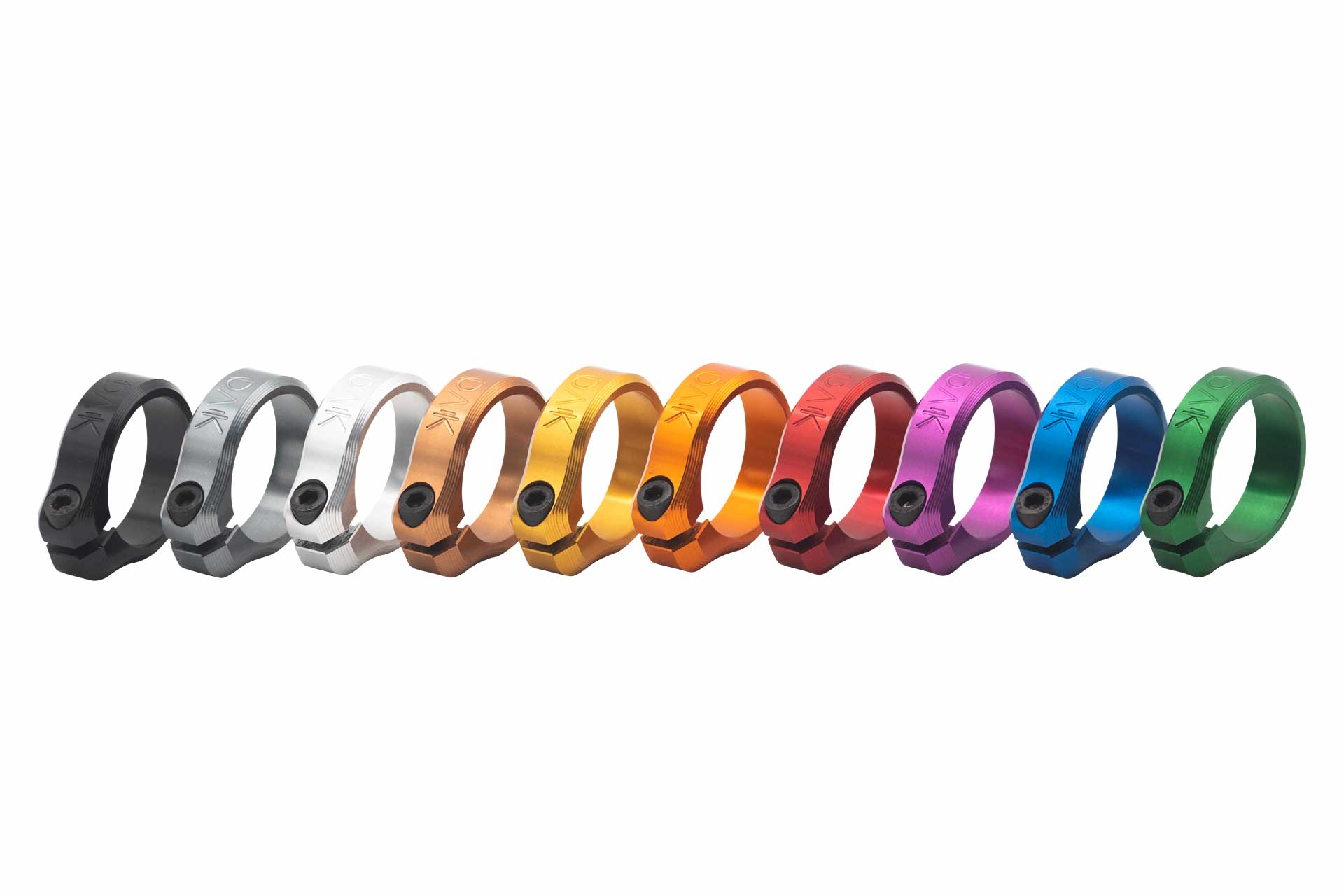 Eleven anodized aluminum mountain bike rings in various colors with engraving, aligned horizontally on white.