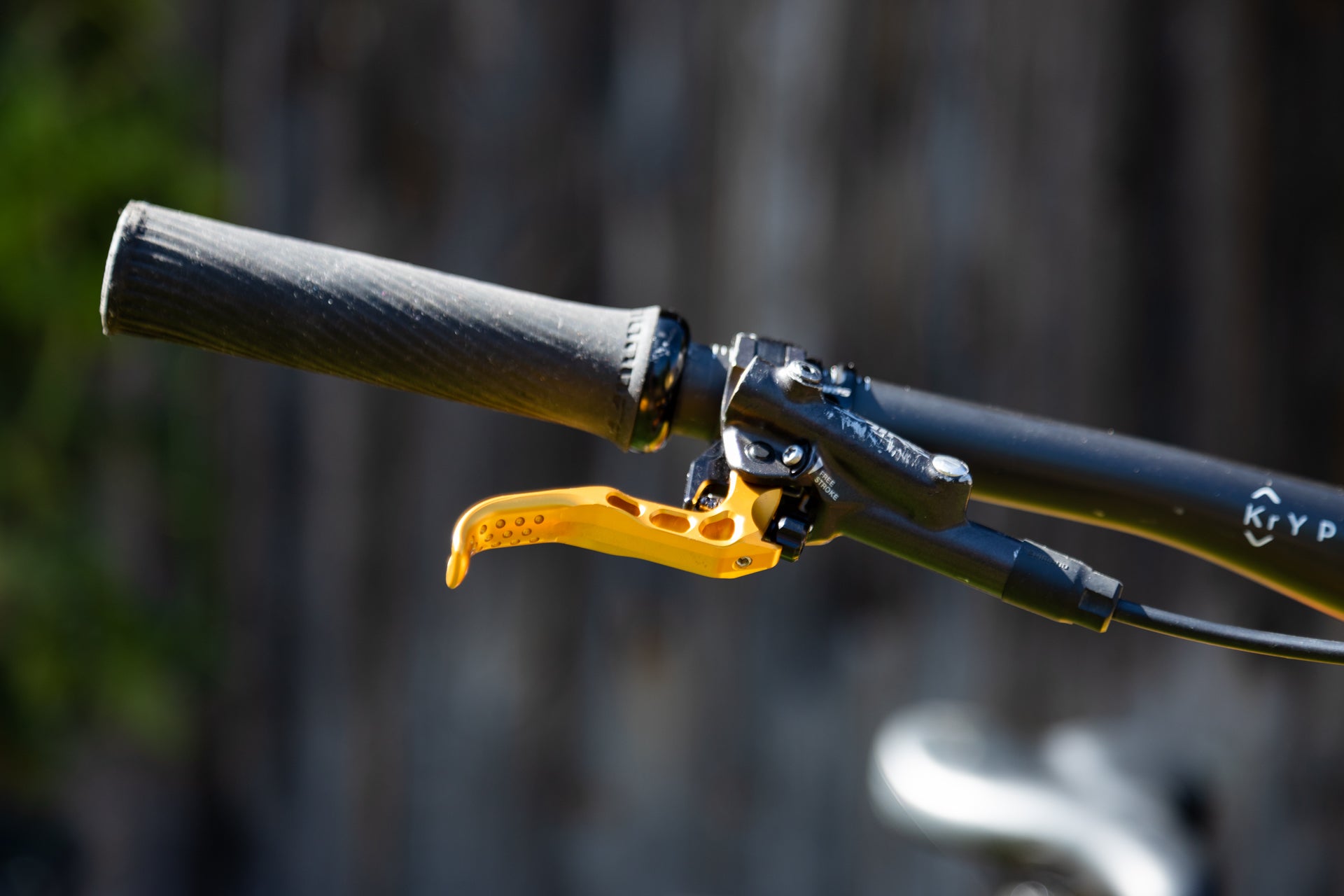Close-up of bicycle handlebar with black grip, yellow FREE STROKE brake lever, and KrY P branded tube.