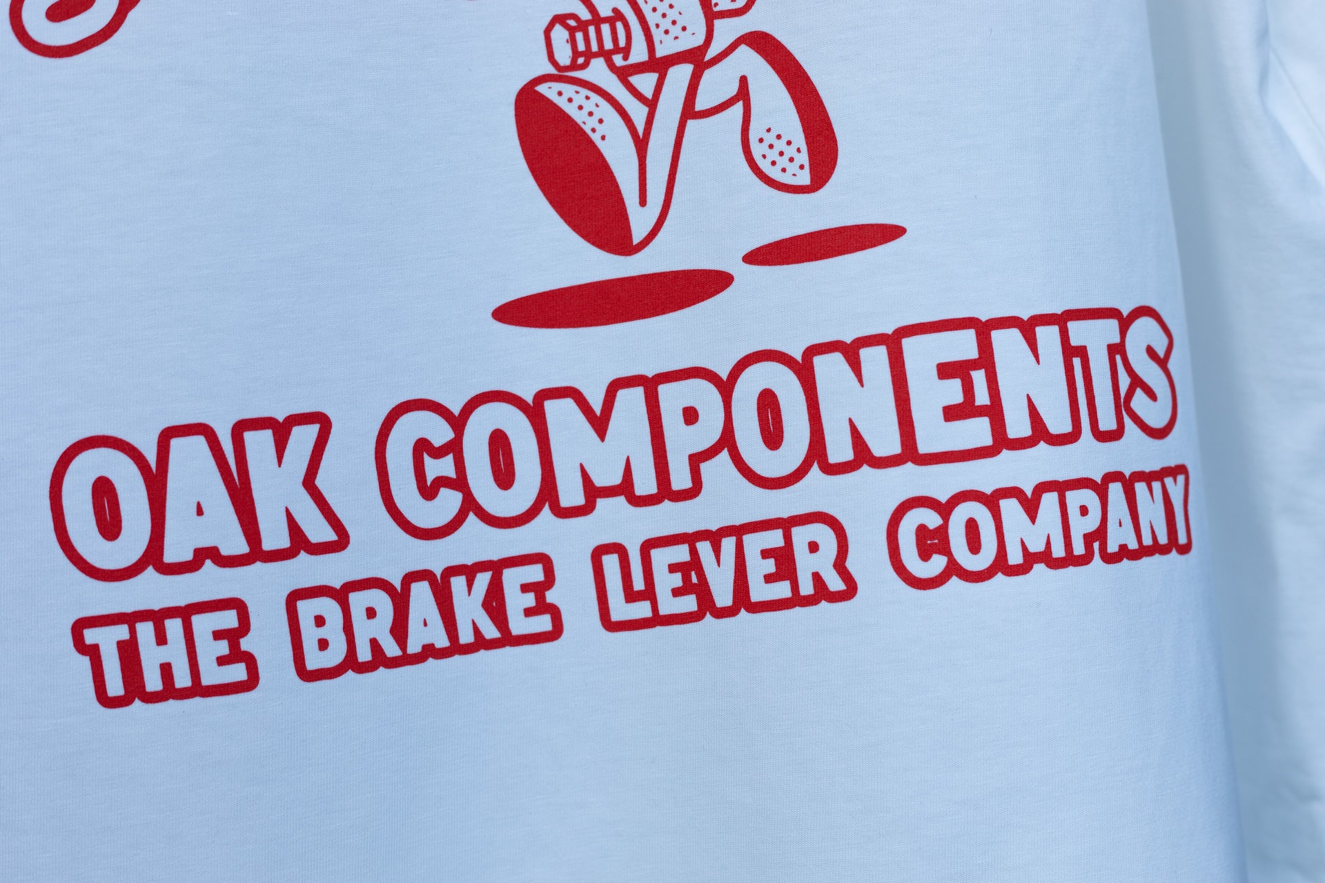 White t-shirt featuring bold red 'OAK COMPONENTS' text and a bicycle brake lever graphic.