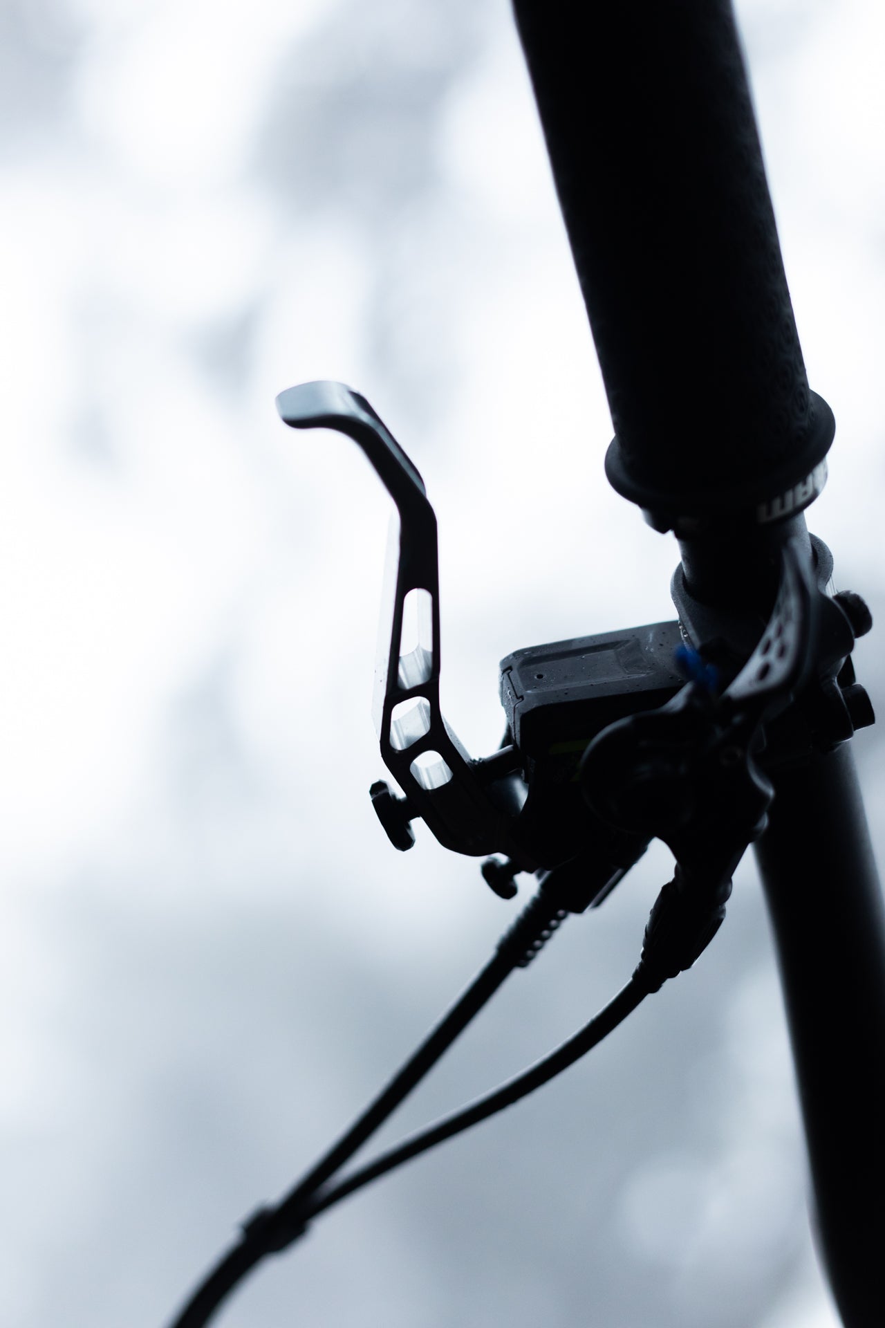 Close-up of a mountain bike brake lever with detailed cutouts and connected cables