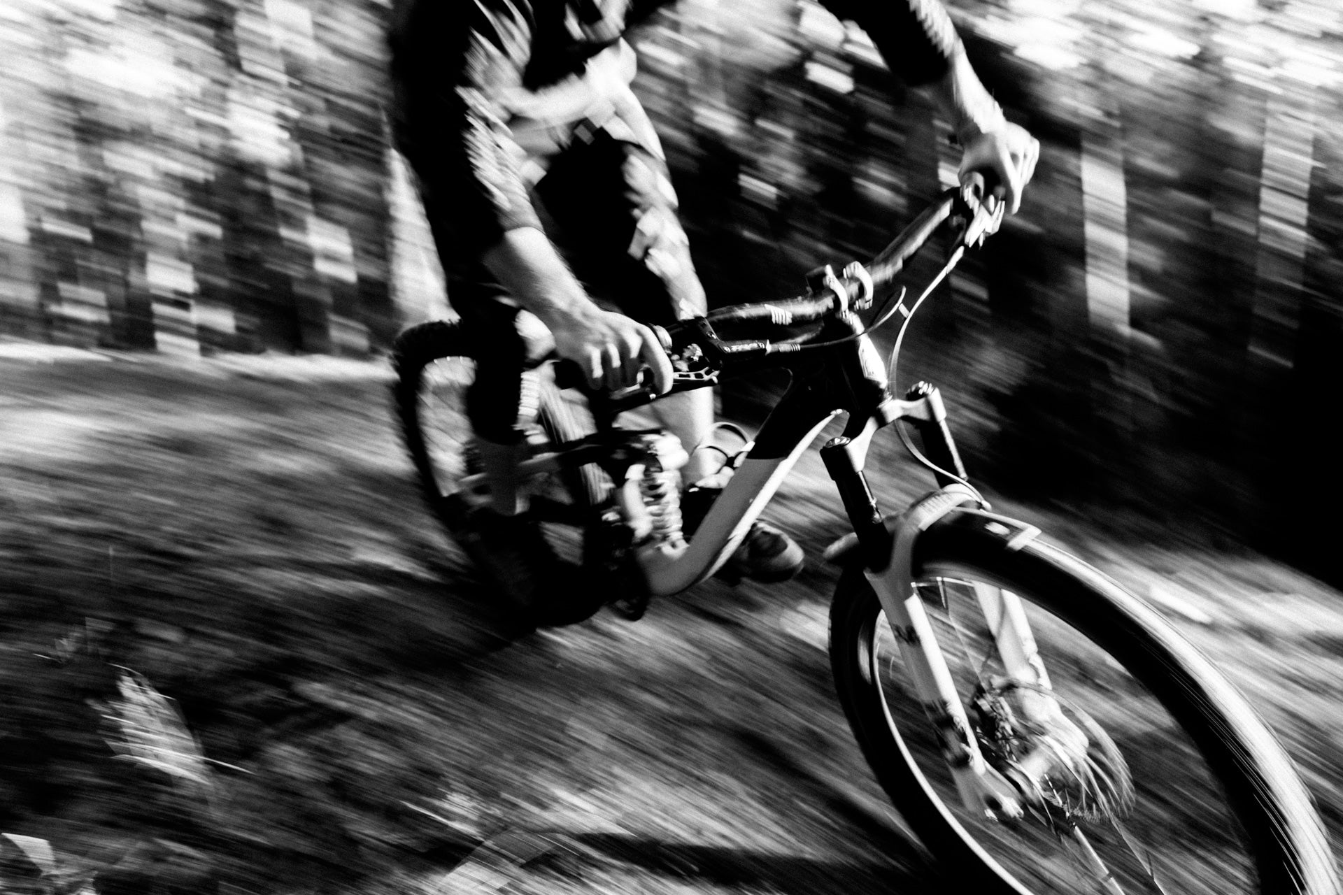 Mountain biker riding a suspension-equipped bike fast through a blurred forest trail