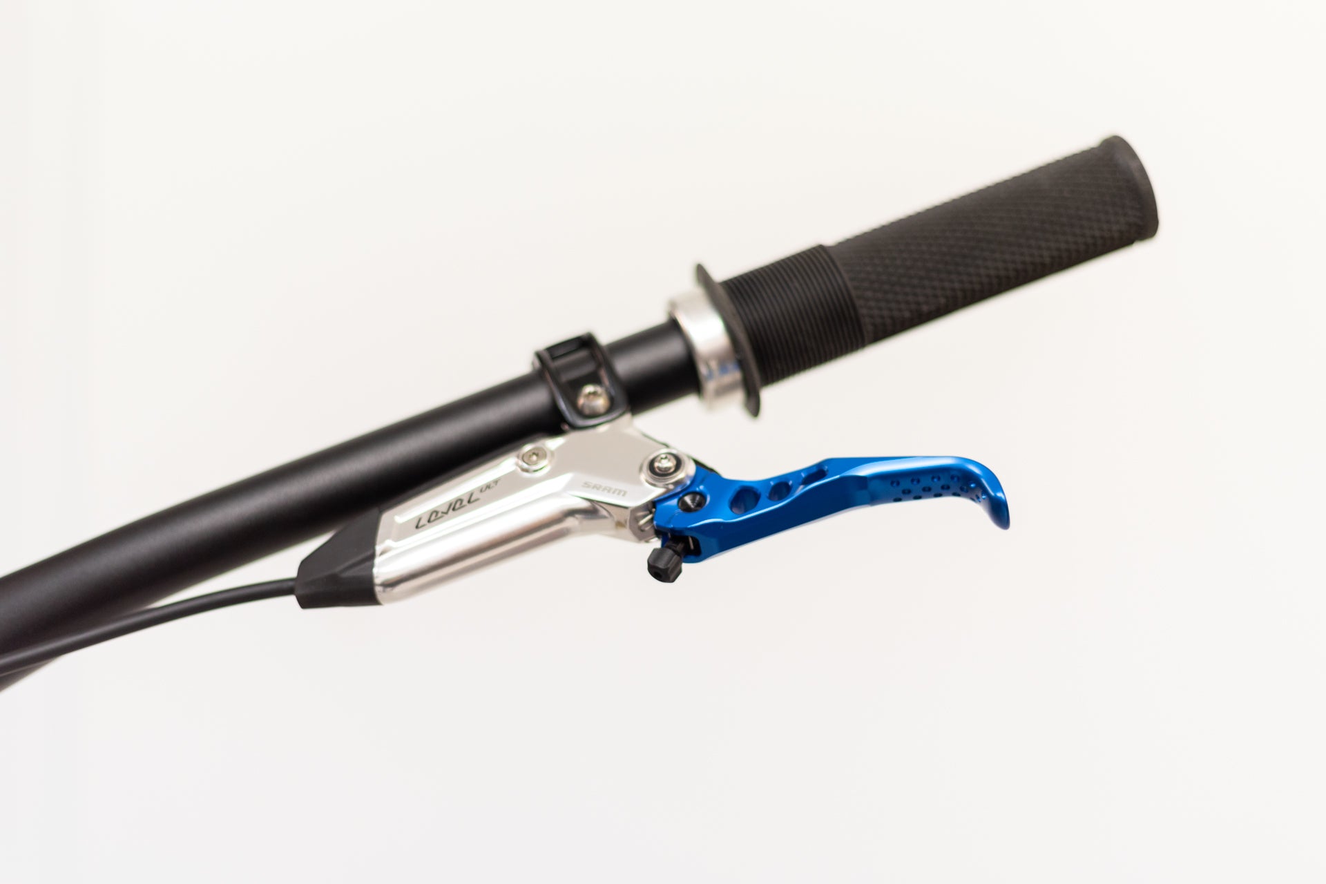 Close-up of a mountain bike handlebar with a black grip and chrome SRAM Level ULT brake lever.