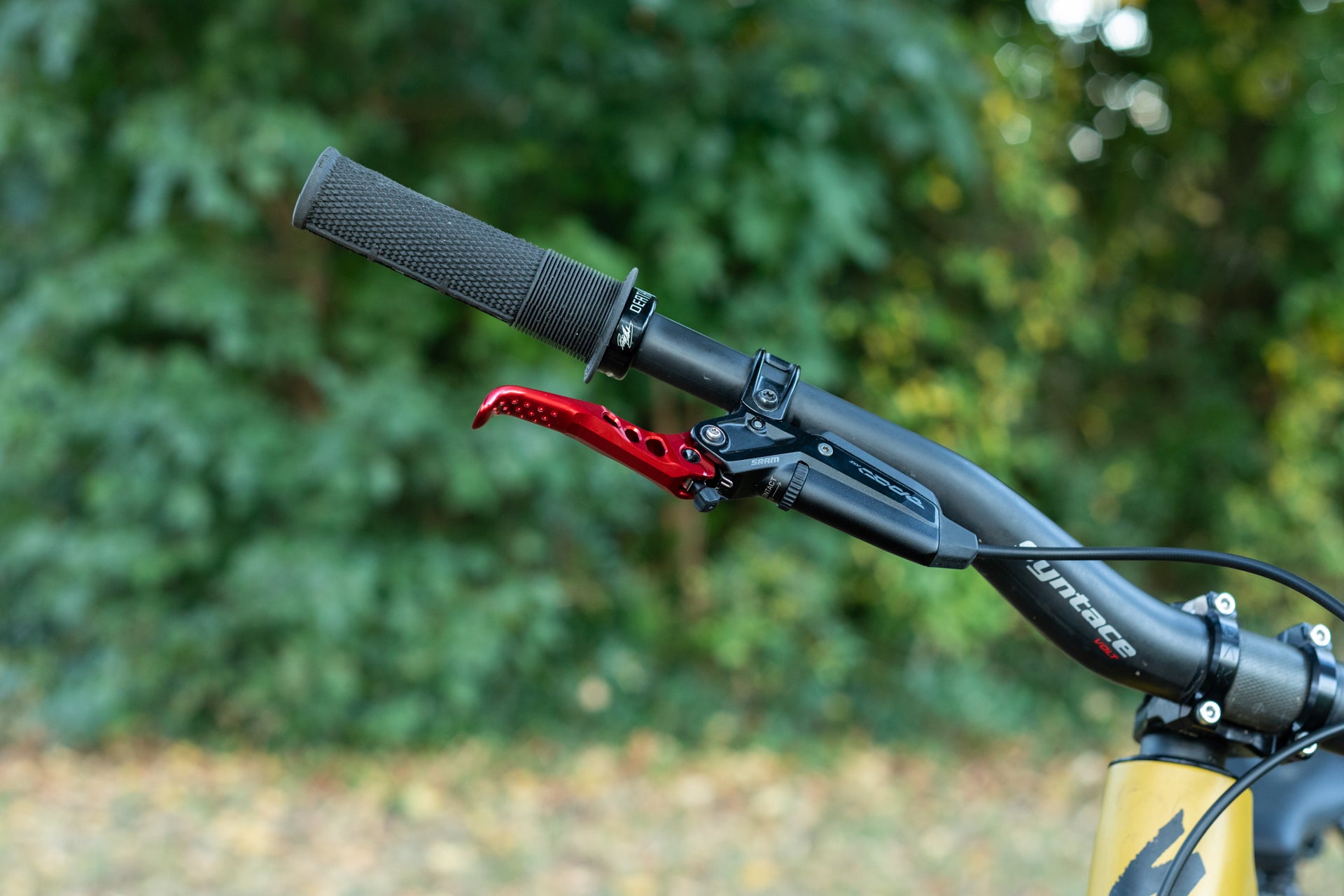 Close-up of matte black yntace VOLT bicycle handlebar with black grip, red brake lever, and SRAM brake housing.