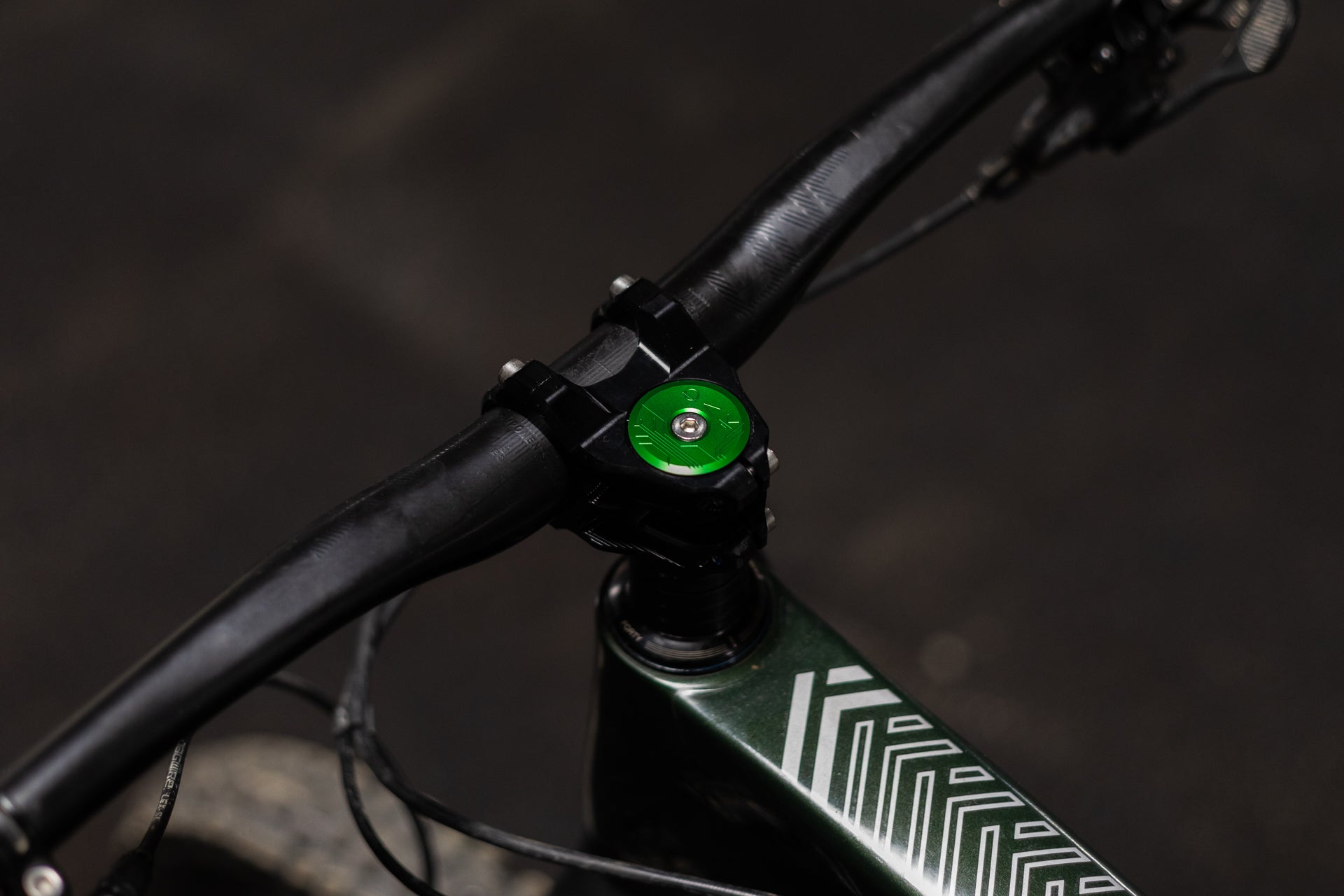 Close-up of a black bicycle handlebar with a green 'FORTY' top cap and a dark green frame with white geometric patterns