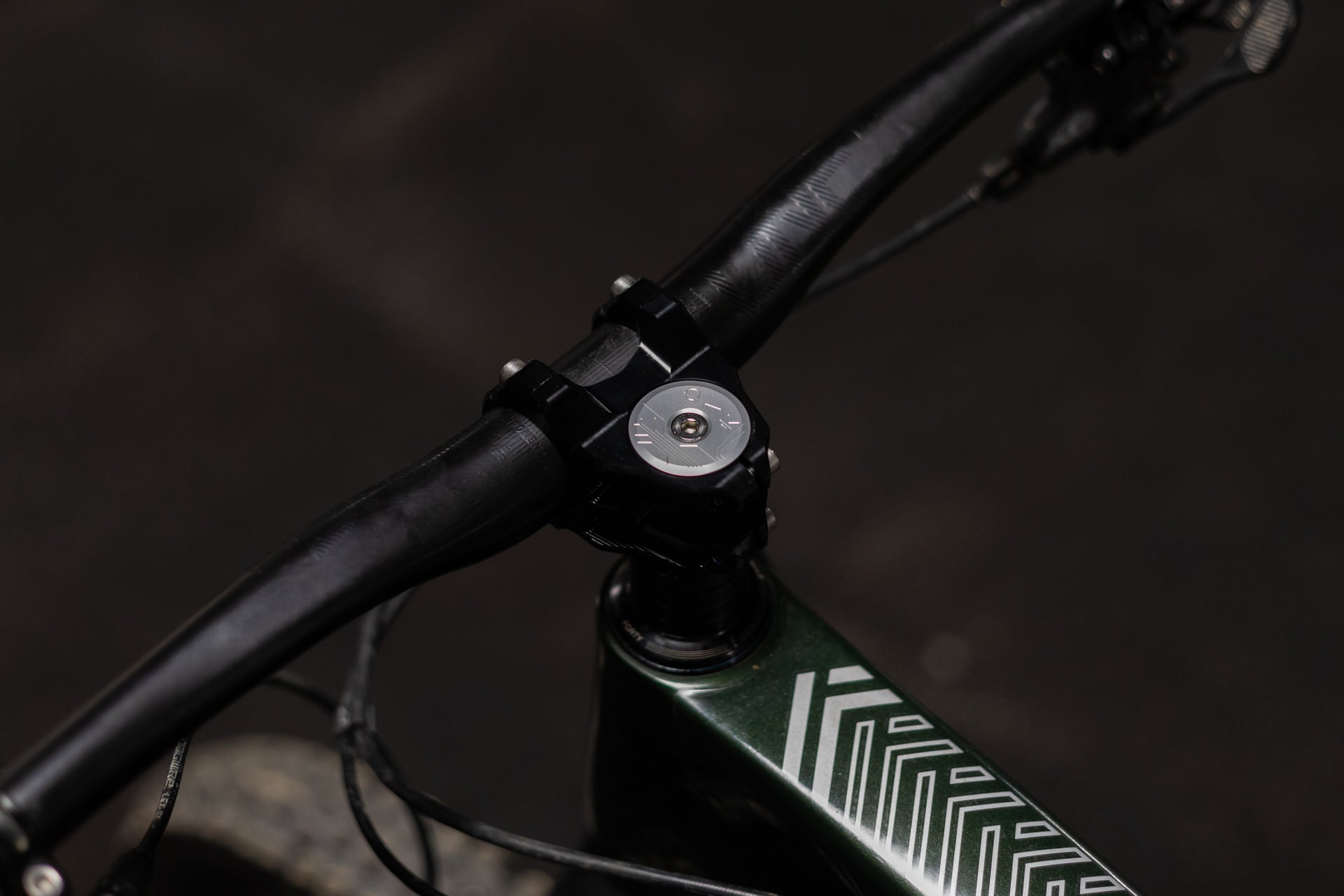 Close-up of FORTY mountain bike handlebar and stem, silver faceplate, dark green frame with white decals.
