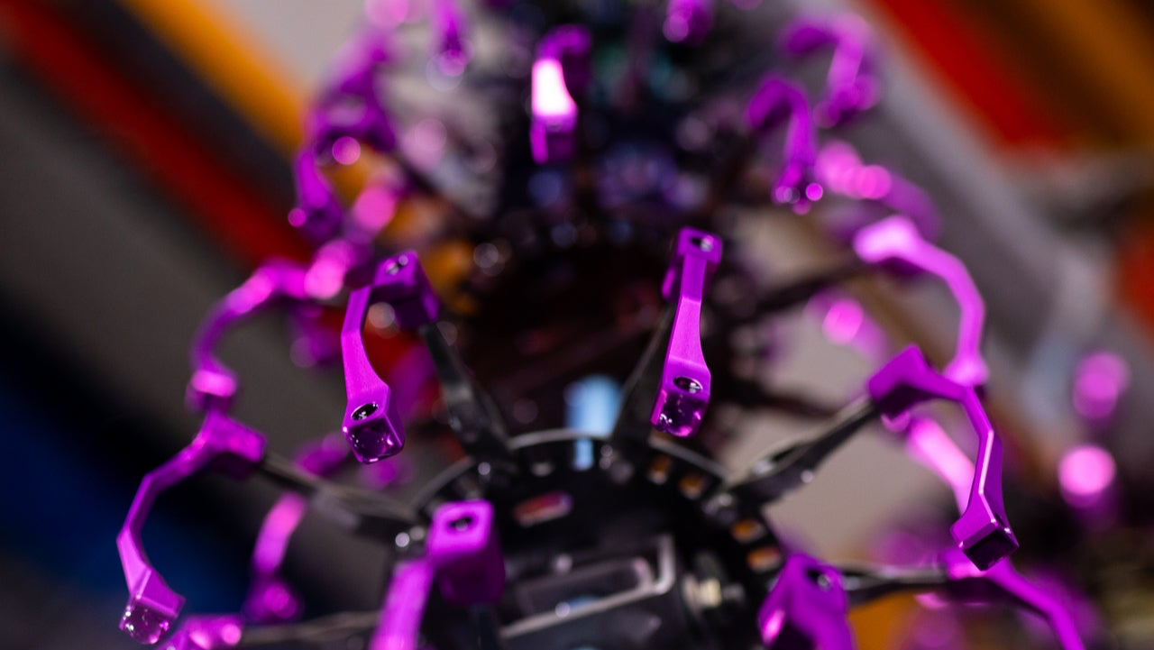 Close-up of a metallic purple mechanical claw with screws around a central black ring, mountain bike component.