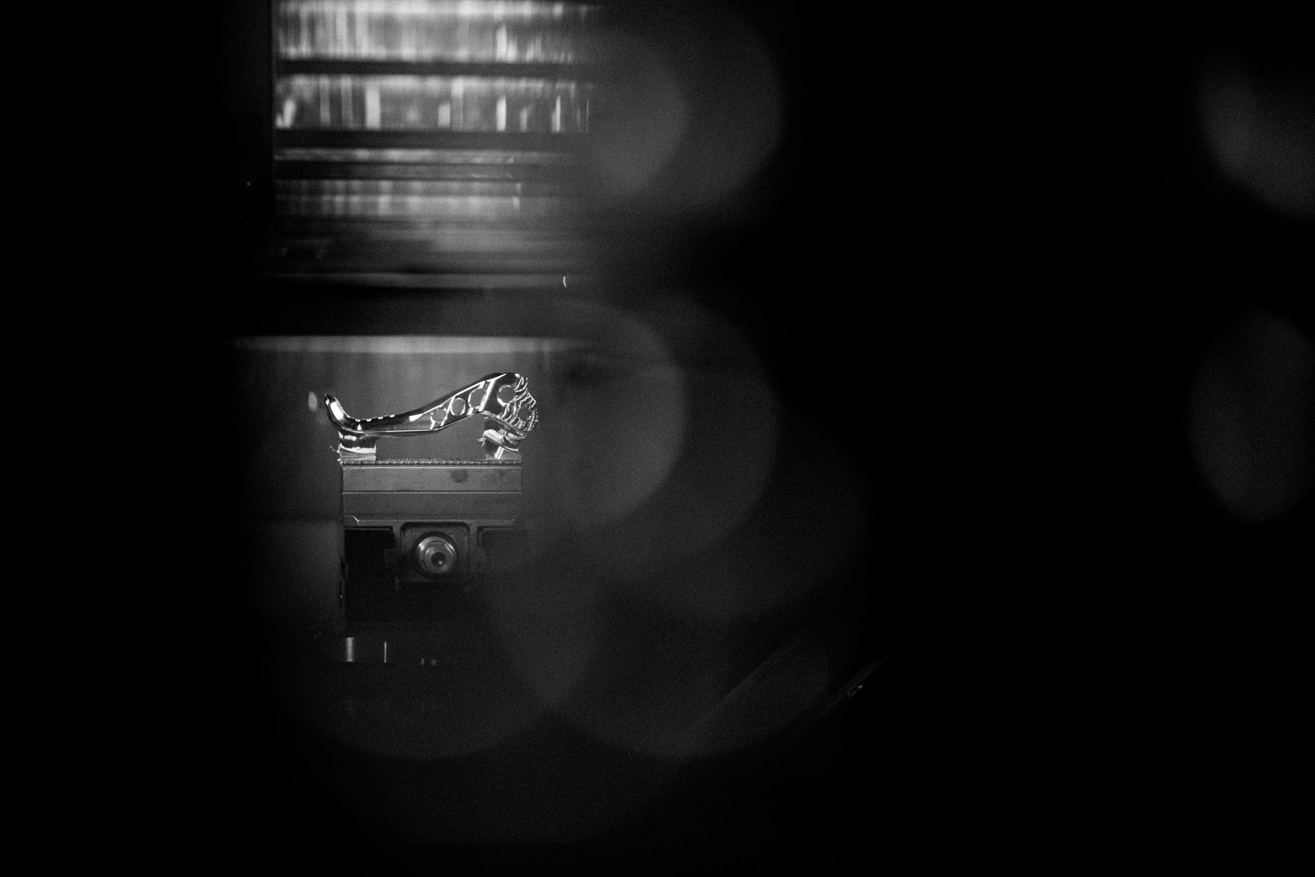 Metallic robotic arm part on a machine base with circular dial in an industrial environment.