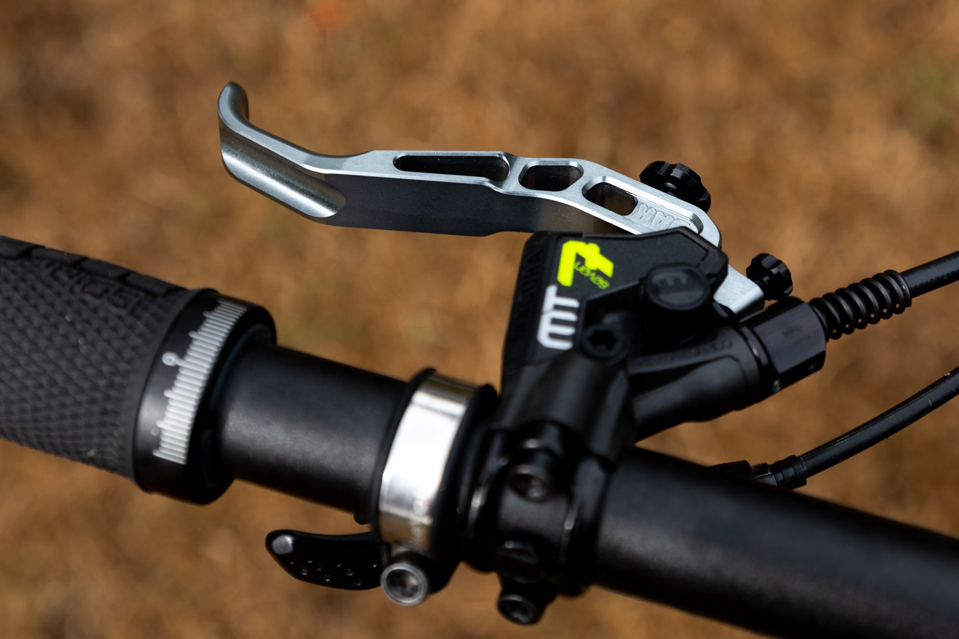Close-up of mountain bike handlebar with silver AK MT7 brake lever and textured black grip.