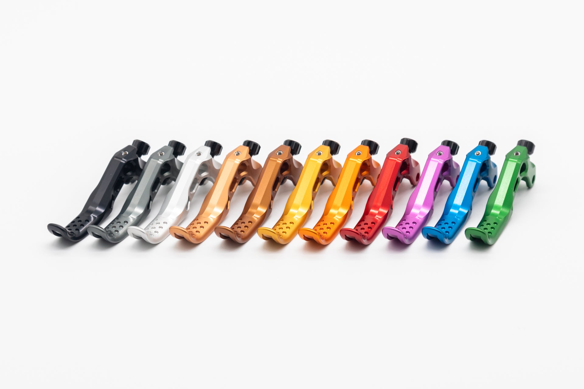 Twelve anodized aluminum bicycle brake levers in a gradient from black to green, with black knobs and perforated grips.