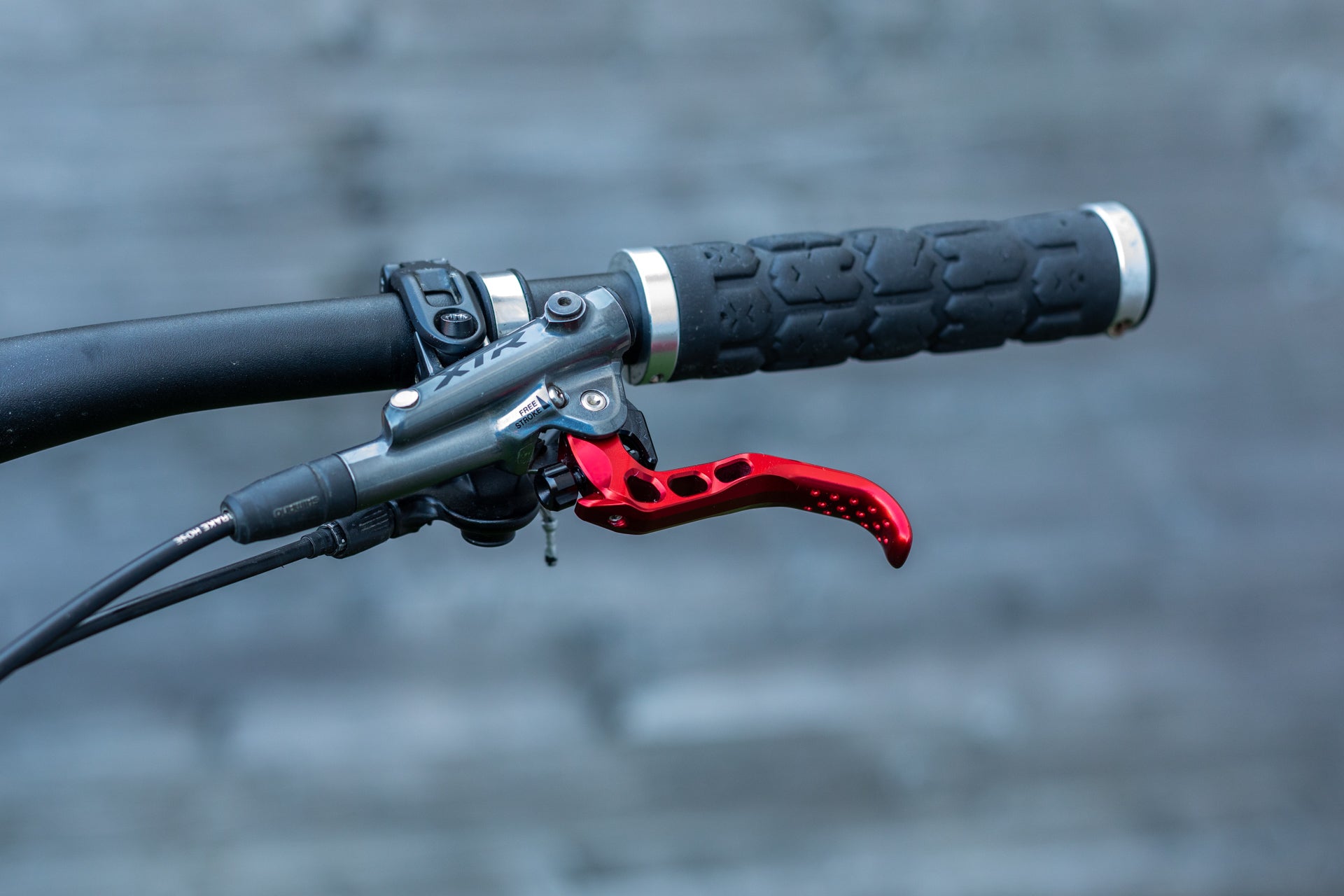 Close-up of a mountain bike handlebar with black grip, silver end caps, and XTR brake lever.