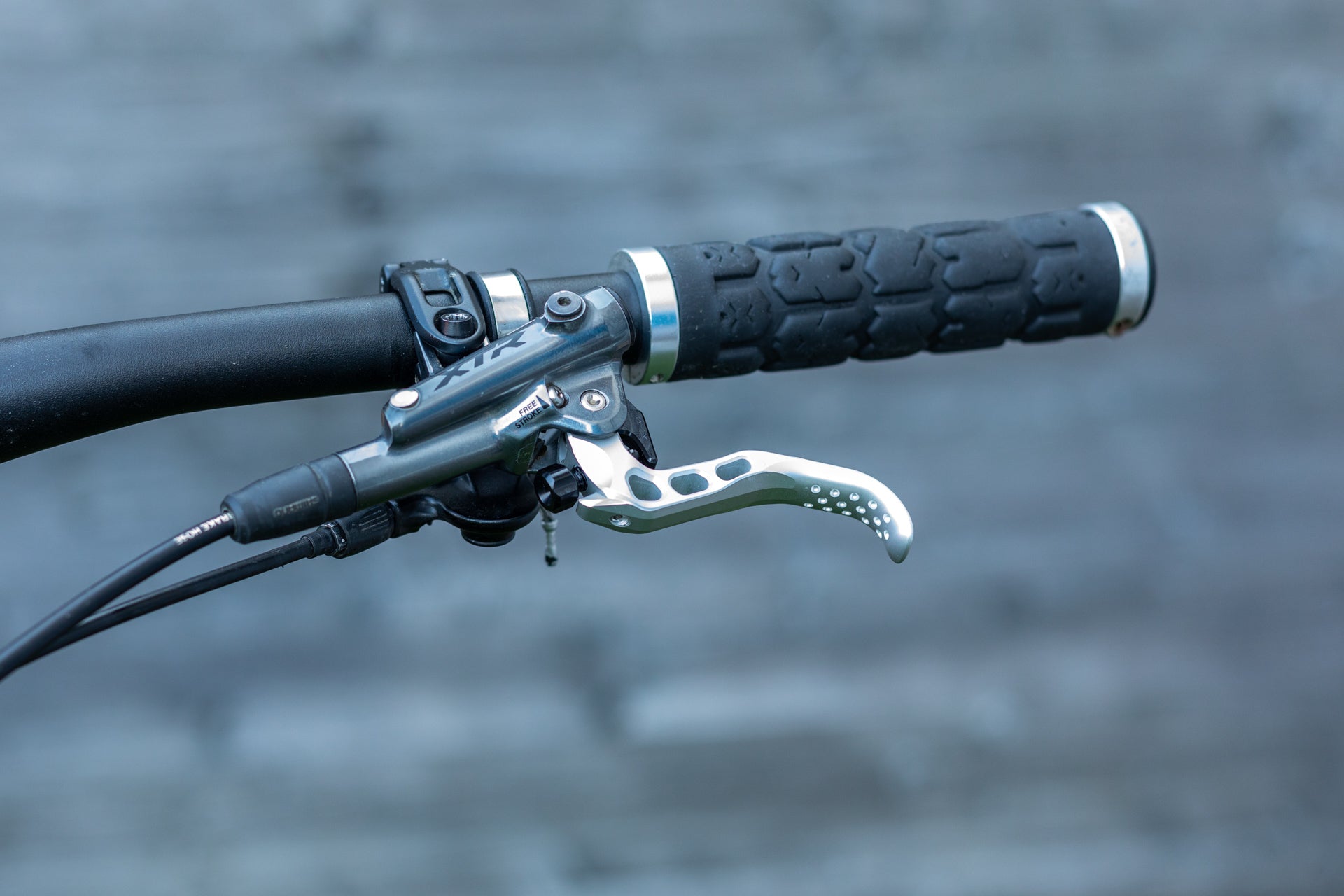 Bicycle handlebar with black grip, silver brake lever, and labeled brake hose.