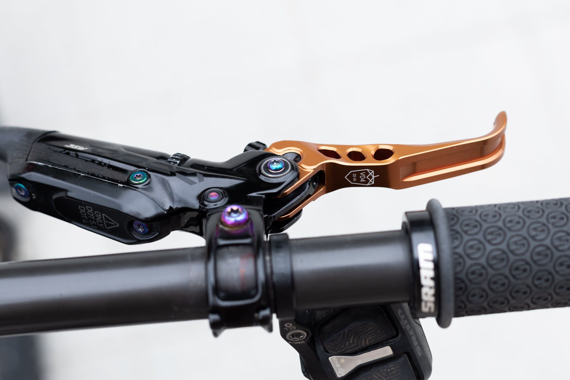 Close-up of a bicycle handlebar with an orange V04 hydraulic brake lever and SRAM black rubber grip.